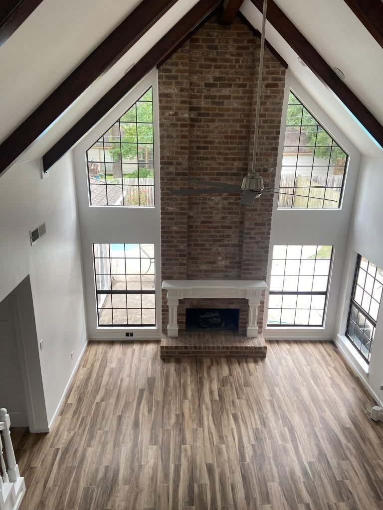 Vaulted residential living space with brick fireplace and exposed beams